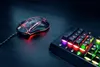 A gaming mouse and a portion of a gaming keyboard with RGB lighting are displayed on a dark surface. Produktbild-Vorschau