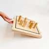 A hand is shown reaching towards a wooden game board with several wooden pieces on it. The board is tilted, showing its side and top. Produktbild-Vorschau