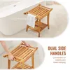 A wooden shower bench with a towel hanging on it, next to a bathtub. Another image shows hands gripping the bench handles. Podgląd zdjęcia produktu