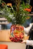 A person is holding a decorative vase filled with flowers. Produktbild-Vorschau