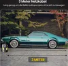 A vintage green car parked on a paved surface with trees and a brick wall in the background. A black and yellow air compressor is placed on the ground near the car's front tire. Produktbild-Vorschau