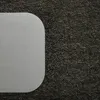 A close-up view of a transparent desk mat with rounded corners placed on a dark, textured carpet. Náhled obrázku produktu