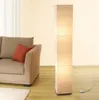 A floor lamp stands next to a sofa in a living room. Produktbild-Vorschau