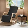 A black rocking chair with a footrest is placed on a rug next to a small black side table with two glasses and a book on it. A window with a view of the sea and greenery is in the background. Voir les images du produit