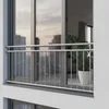A balcony railing in front of a window overlooking a city skyline. Podgląd zdjęcia produktu