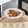 A hand is holding a plate of food in front of an open microwave. Náhled obrázku produktu