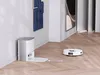 A robot vacuum cleaner is returning to its charging dock in a modern living room. Voir les images du produit