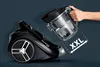 A hand is holding a detached dustbin of a vacuum cleaner next to the main body of the vacuum cleaner. Produktbild-Vorschau