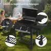 People enjoying a barbecue in a backyard setting with a charcoal grill. Produktbild-Vorschau
