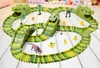 A toy dinosaur race track with toy dinosaurs and a toy car. Produktbild-Vorschau