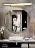 A modern bathroom vanity with a round mirror, a sink, and a wall light. Produktbild-Vorschau