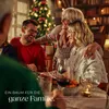 A family is gathered around a table for a Christmas dinner, with a decorated Christmas tree in the background. Náhled obrázku produktu