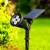 A solar-powered garden spotlight is shown in a grassy outdoor setting with green foliage in the background. Voir les images du produit