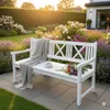 A white garden bench with a blanket, book, and teacup sits in a lush garden with blooming flowers and a sunset. Produktbild-Vorschau
