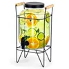 A glass beverage dispenser with a spigot and a metal stand, filled with water and fruit slices. Produktbild-Vorschau