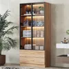 A tall, narrow cabinet with glass doors and LED lighting, filled with folded towels and toiletries, stands in a bathroom setting next to a potted plant. Voir les images du produit