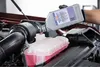 A person is pouring coolant into a car's engine. Produktbild-Vorschau