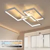 A modern ceiling light fixture with multiple rectangular frames, illuminated and mounted on a ceiling. The image also shows a window with blinds and a remote control. Náhled obrázku produktu