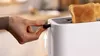A hand is shown operating a white toaster with two slices of toast inside. Produktbild-Vorschau
