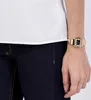 A woman's arm wearing a gold watch and dark blue jeans, with a white top visible. Podgląd zdjęcia produktu