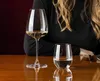 A person's torso and hair are visible behind two glasses of white wine and water on a wooden table. Produktbild-Vorschau