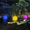 Three illuminated spheres floating in a pond at night, surrounded by plants and lily pads. Produktbild-Vorschau