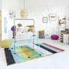 A child's bedroom with a crib, gym bar, and colorful rug. Voir les images du produit