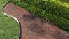 A curved metal garden edging separates a lawn from a mulched flower bed and a hedge. Náhled obrázku produktu