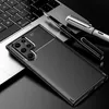 A smartphone case with a carbon fiber texture is placed on a laptop keyboard, next to two pens. Produktbild-Vorschau