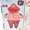 The image shows a product packaging for a doll's winter outfit. The outfit, including a hooded jacket and pants, is displayed prominently. Accessories like sunglasses are also visible. Produktbild-Vorschau