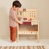 A young boy is playing with a wooden workbench. Produktbild-Vorschau