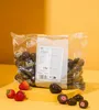 A bag of chocolate-covered strawberries and some loose strawberries are displayed on a yellow platform against a yellow and orange gradient background. Produktbild-Vorschau