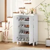 A white shoe cabinet with its doors open, displaying shoes on shelves, placed near a staircase and a plant. Produktbild-Vorschau