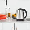A stainless steel electric kettle sits on a kitchen counter next to a bowl of fruit and a red casserole dish. Produktbild-Vorschau