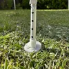 A close-up view of the base of a white tent pole standing in grass. Produktbild-Vorschau
