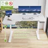 A white L-shaped standing desk with dual monitors, keyboard, and tablet, set against a window with a view of palm trees. Anteprima dell’immagine prodotto