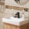 A bathroom sink with a black faucet and a white soap dispenser. Produktbild-Vorschau