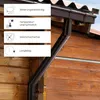 A close-up of a brown gutter downspout attached to a wooden building, with four white informational boxes on the left detailing product features. Produktbild-Vorschau