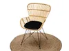 A rattan chair with a black cushion sits on a round jute rug. Produktbild-Vorschau