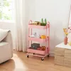 A pink three-tiered rolling cart filled with various items, placed in a room next to a sofa and a cabinet. Anteprima dell’immagine prodotto