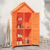 An orange wooden garden shed with its doors open, showing shelves stocked with various items like pots, buckets, and boxes. Gardening tools are leaning against the side of the shed. Podgląd zdjęcia produktu