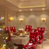 A dining room set for Christmas with a decorated tree and festive chair covers. Náhled obrázku produktu