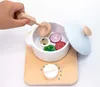 A child's hand is adding wooden vegetables to a toy pot on a toy stove. Podgląd zdjęcia produktu