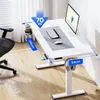 A white standing desk with a computer monitor, keyboard, and mouse on it. The desk has measurement indicators and weight capacity information displayed. Podgląd zdjęcia produktu