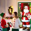 Two children in festive attire are exchanging gifts in a decorated room with Christmas decorations. Produktbild-Vorschau