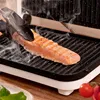A piece of salmon is being grilled on an electric grill, with steam rising from the food. Voir les images du produit