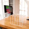 A white wire rack designed to hold records or books is placed on a wooden desk next to a computer monitor. Anteprima dell’immagine prodotto