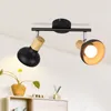 A black ceiling light fixture with two adjustable spotlights, each with a wooden accent, mounted on a white ceiling. Voir les images du produit
