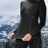 A person wearing a black long-sleeved thermal shirt and leggings in a snowy mountain environment. Náhled obrázku produktu