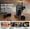 A manual arbor press and related tools are displayed on a wooden table, with examples of its applications shown in smaller inset images below. Podgląd zdjęcia produktu
